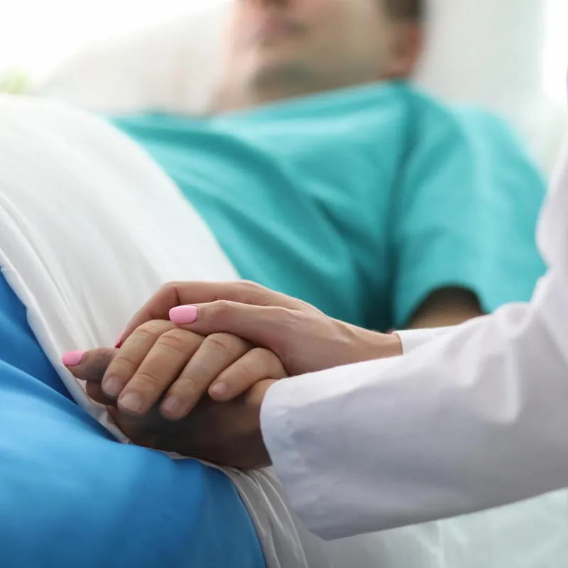 A caregiver holding a patient’s hand